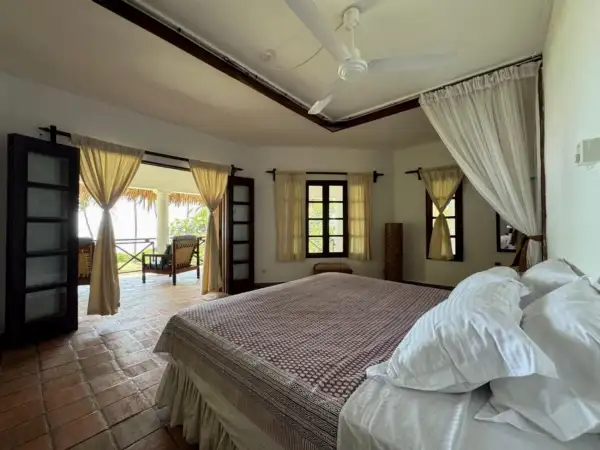Bedroom with four-poster bed and doors opening onto a veranda