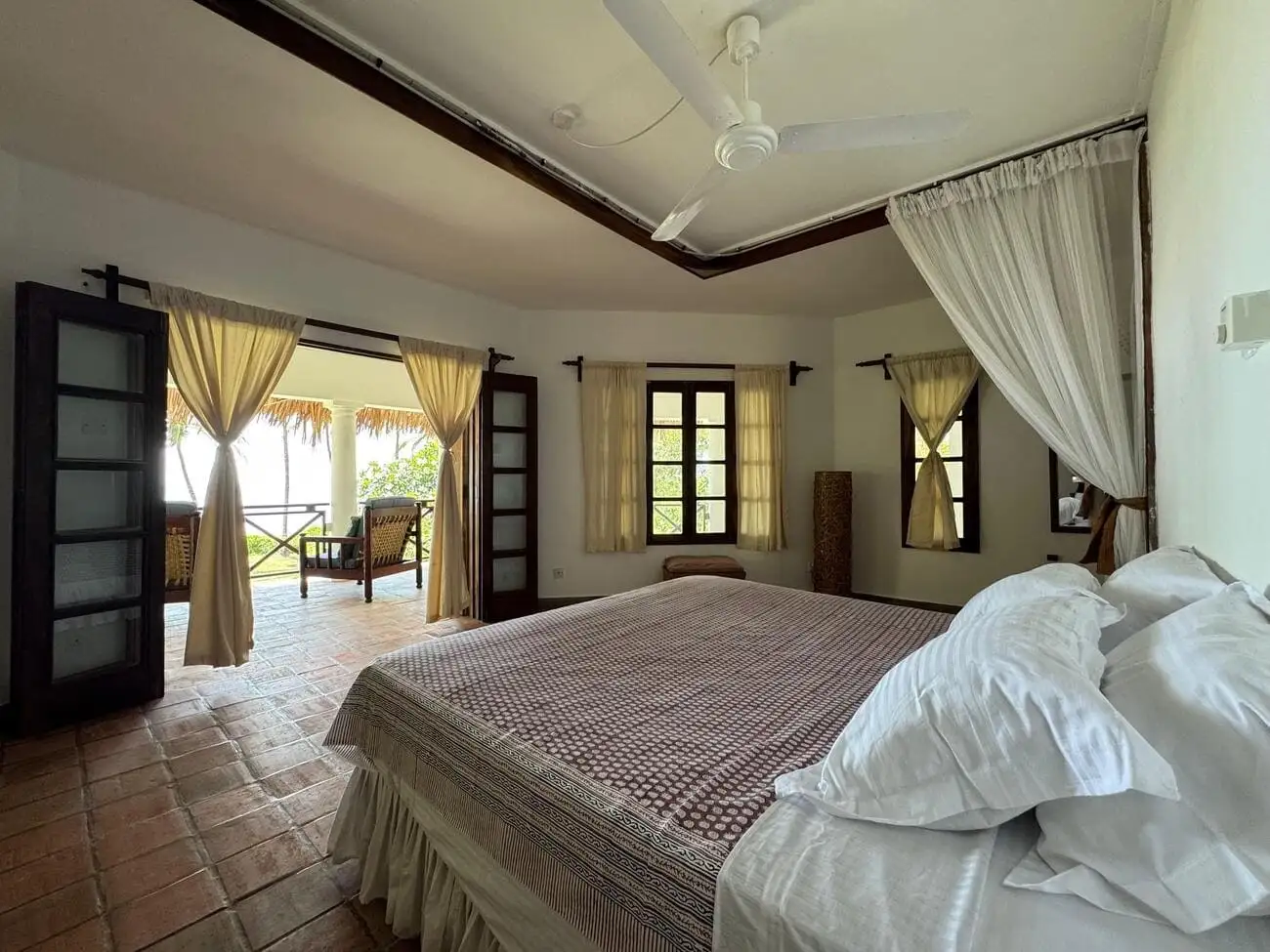 Bedroom with four-poster bed and doors opening onto a veranda