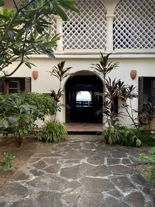 Courtyard entrance with Swahili lattice and an arched doorway looking through to the ocean