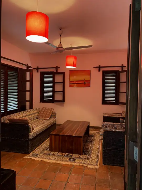 Snug sitting room with shuttered windows, terracotta floor and warm pendant lamps