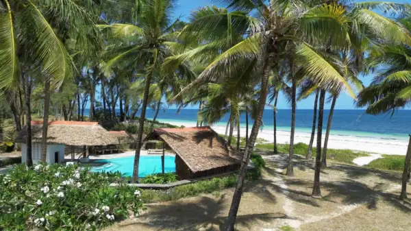 View over the pool and thatched roofs to the beach