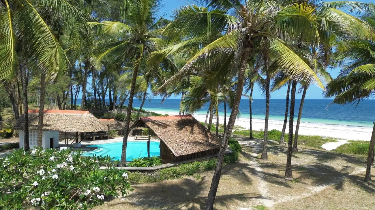 View over the pool and thatched roofs to the beach