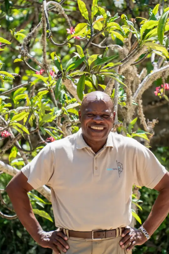 A smiling member of the Enkare Bofa team in the tropical garden