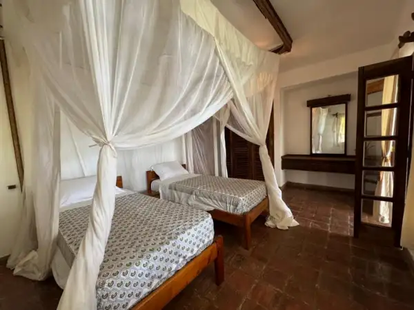 Twin bedroom with mosquito-net canopies and terracotta floors